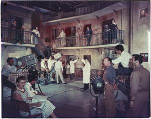 In primo piano è visibile una donna con in mano degli spartiti musicali<br>