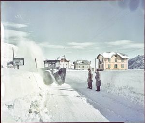 Sono visibili alcune abitazioni e l'Albergo Miramonti. Sulla sinistra un cartello dell'ANAS con la scritta: Passo Tonale alt. 1883<br>