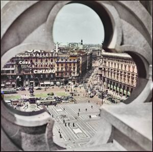 Automobili ed autobus attraversano la piazza. Sul palazzo di fronte sono appese numerose insegne pubblicitarie: Cinzano, Cora, Bosca, Valletti, Espresso Bonomelli, Brill, Venus, Kaloderma, Martini<br>